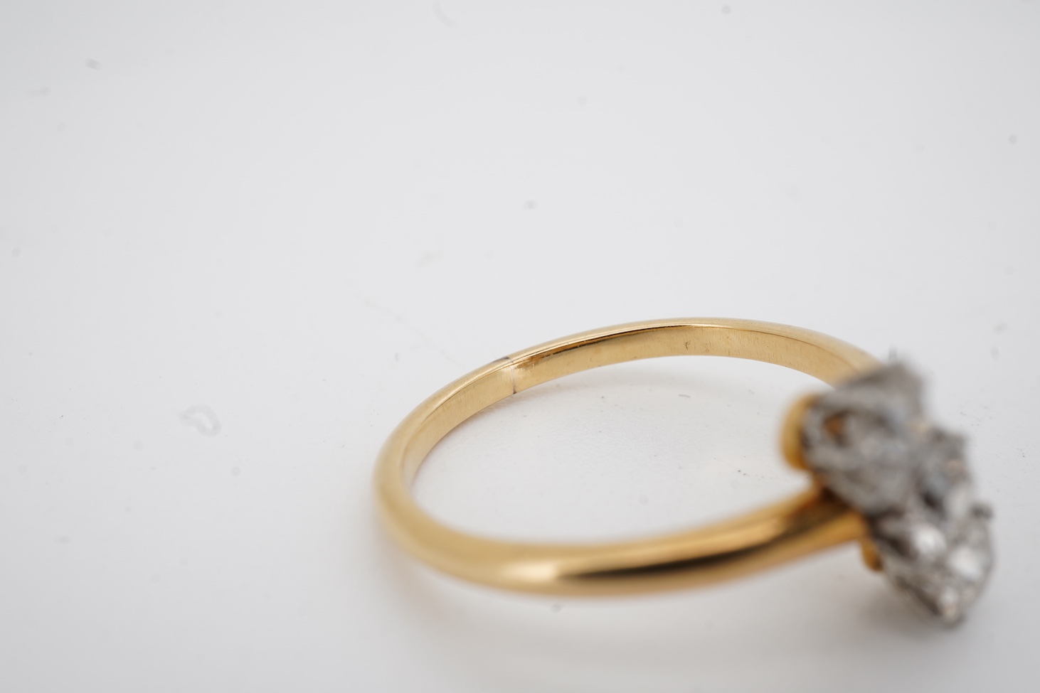 A mid to late 20th century yellow metal and three stone diamond set crossover ring, total diamond weight approx. 0.45-0.50ct, size K, gross weight 2.5 grams.